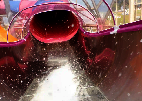 Blick durch den Speed Blaster, Wasser spritzt beim Rutschen aus der Tunnelöffnung.