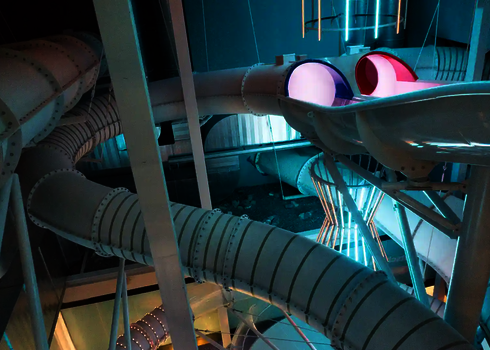 Mehrere weiße Wasserrutschen in einem Hallenbad.