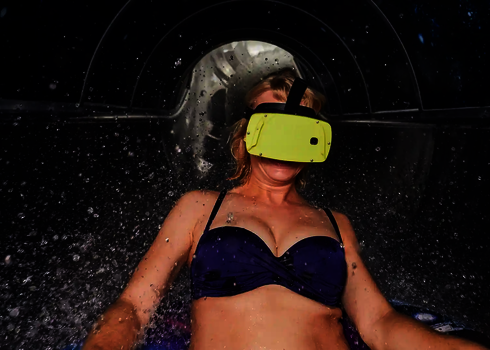 Oberkörper einer Frau in Bikini mit VR-Brille im inneren einer Wasserrutsche.