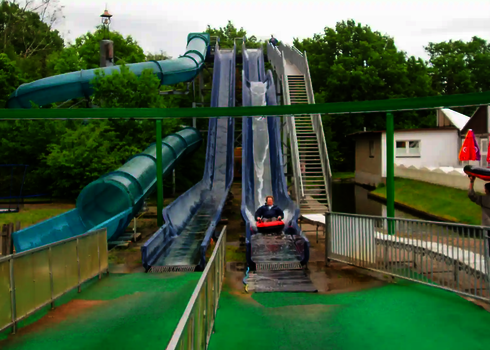 Harakiri Freizeitparkrutsche und weitere Wasserrutschen in parkähnlicher, grüner Umgebung.