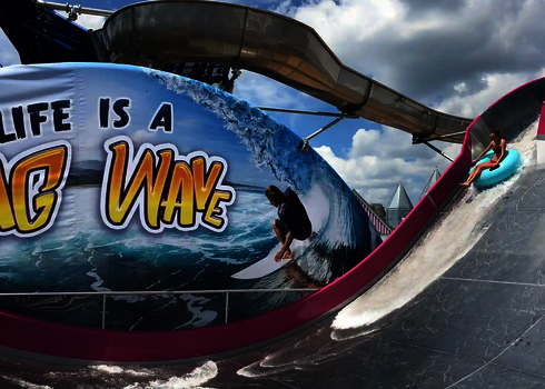 Eine Frau fährt mit einem blauen Reifen auf der Sidewinder an einem Surferbild vorbei.