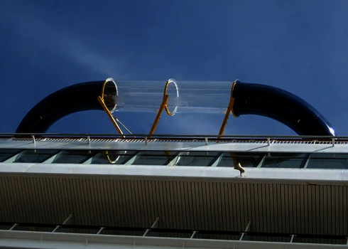 Seitliche Außenansicht einer Wasserrutsche mit mittigem Acryl-Element auf einem Kreuzfahrtschiff.