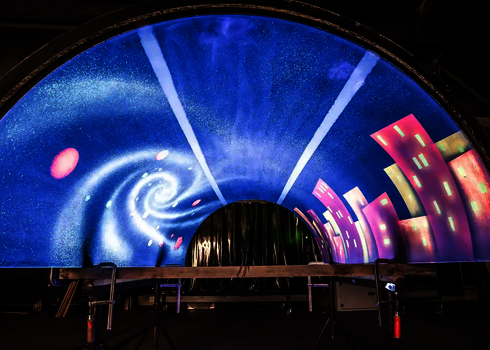 Röhrensegment mit UV-Malerei zeigt Spirale und Häuser, montiert zur Präsentation.