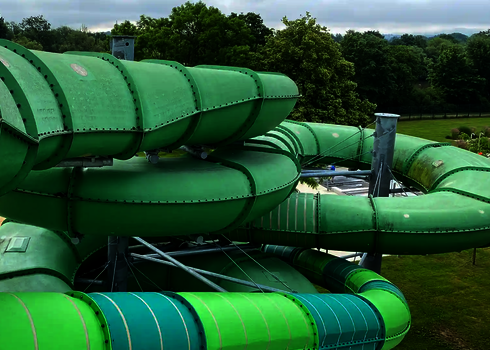 Gedämmte grüne Wasserrutsche schlängelt sich durch eine grüne Parkanlage.