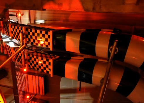 Body Racer Röhren mit Schachbrettmuster und oranger Beleuchtung an der Wand.