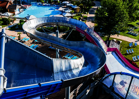 Luftaufnahme eines Wasserparks mit Crazy River Reifenrutsche und mehreren Schwimmbecken.