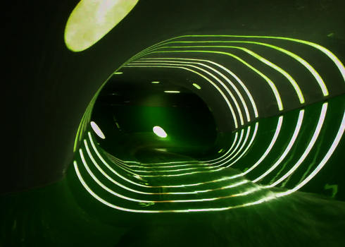 Innenansicht einer Wasserrutsche mit Tageslichteffekten in Form von Streifen und Punkten.