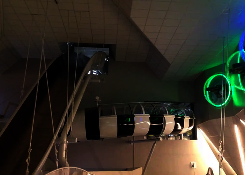 Rutschentunnel der Boomerang-Rutsche mit LED-Lichtringen an der Wand und steiler Rampe.