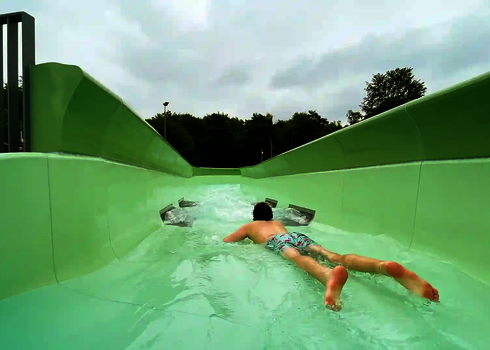 Ein Mann gleitet bäuchlings durch den grünen Wildwasserfluss im Außenbereich.