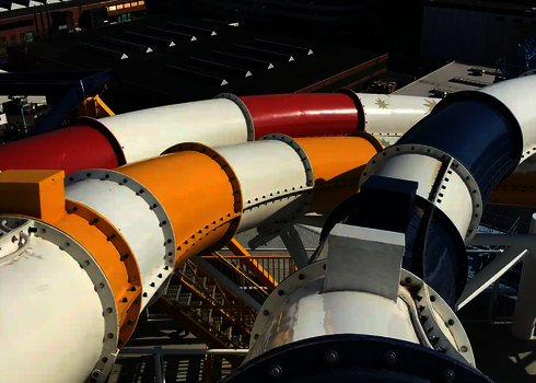 Mehrere Wasserrutschen verlaufen bunt geschwungen über das Deck eines Schiffes im Hafen.