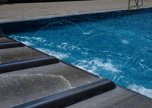 Spritzwasserfontänen am Auslauf einer Multilane Wasserrutsche im Freibad.