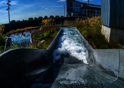 Wildwasserfluss endet in einem Sammelbecken mit mehreren Personen unter freiem Himmel.