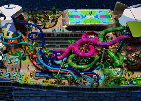 Deck eines großen Kreuzfahrtschiffes mit mehreren bunten Wasserrutschen, darunter die grüne Lotus Reifenrutsche.