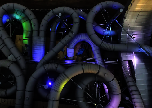  Beleuchtete Röhren des Raft Racer bei Nacht mit blau-violetter Lichtstimmung.