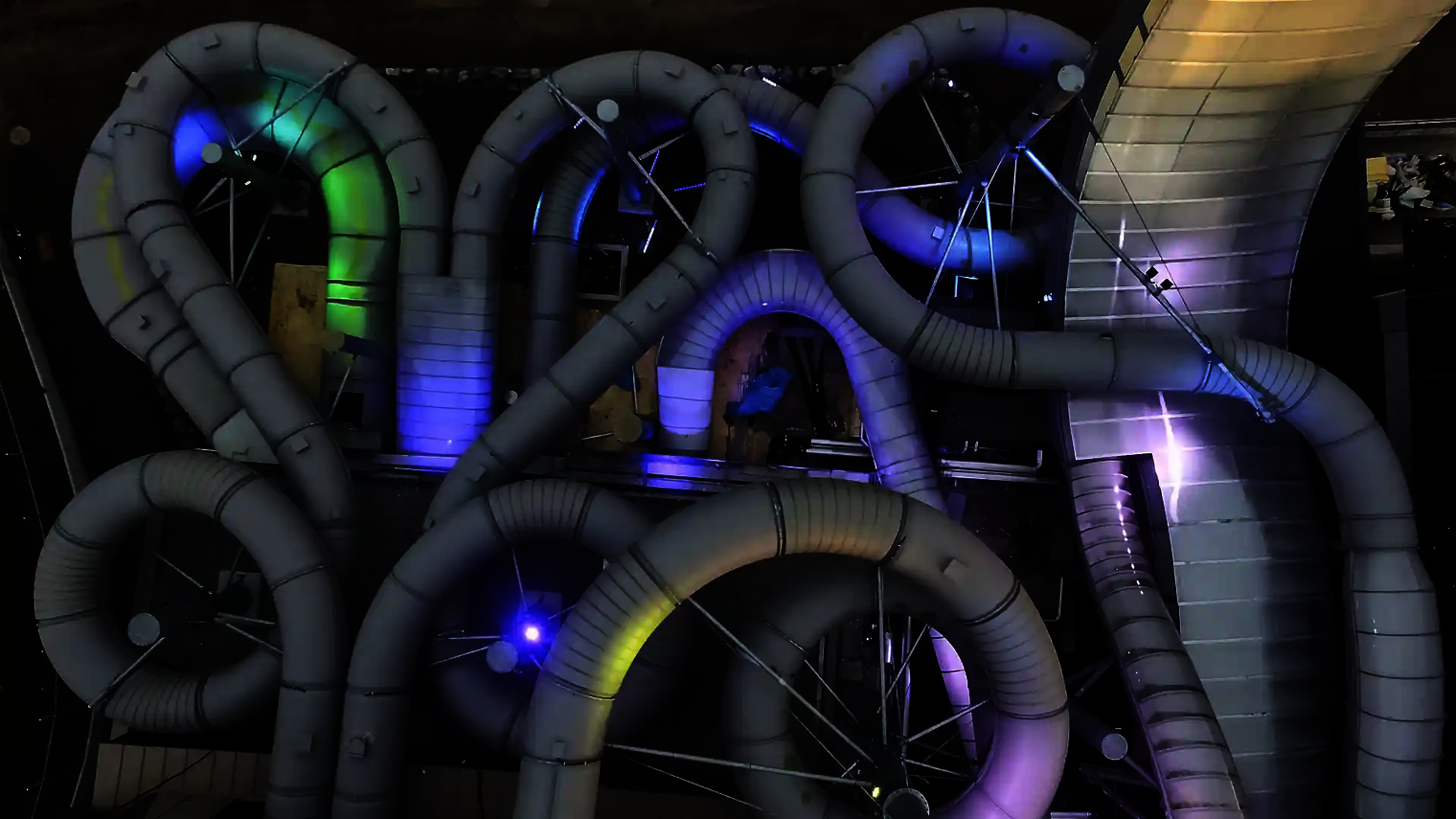 Beleuchtete Röhren des Raft Racer bei Nacht mit blau-violetter Lichtstimmung.