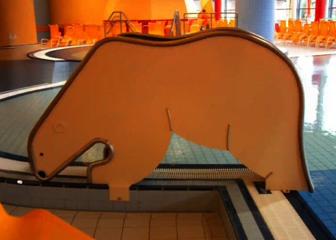  Seitenansicht einer Kleinkinderrutsche in Eisbärenform am flachen Kinderbecken.