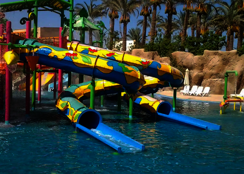 Bunte RR900-Kids Wasserrutsche in tropischen Wasserpark mit Palmen.