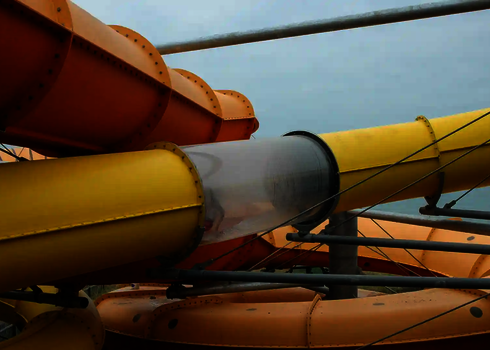 Eine gelbe und eine orangefarbene Wasserrutsche mit Stahlträgern.