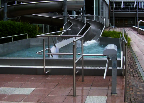 Double outlet made of stainless steel in an outdoor area with access control and water basin.