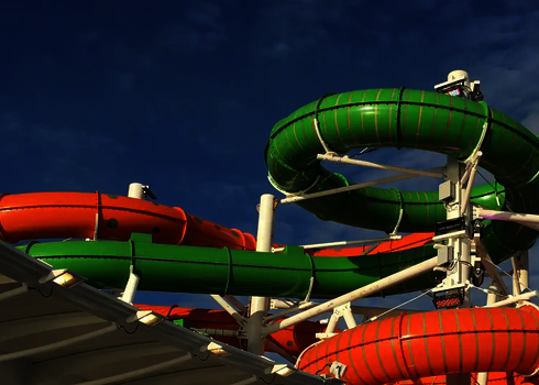 Nahaufnahme von grün-orangen Röhrenrutschen mit glatter Oberfläche bei Sonnenschein.