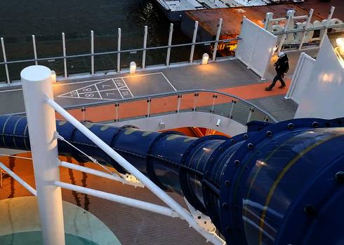 Obenansicht einer blauen Wasserrutsche die von weißen Stahlstützen auf einem Kreuzfahrtschiff getragen wird.