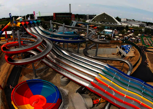 Luftaufnahme eines Wasserparks mit bunten Rutschen, unter anderem einem Matracer und einer Body Bowl.