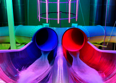 Die Raft Racer Reifenrutsche mit blau-roten Röhren und bunter LED-Beleuchtung in der Startzone.