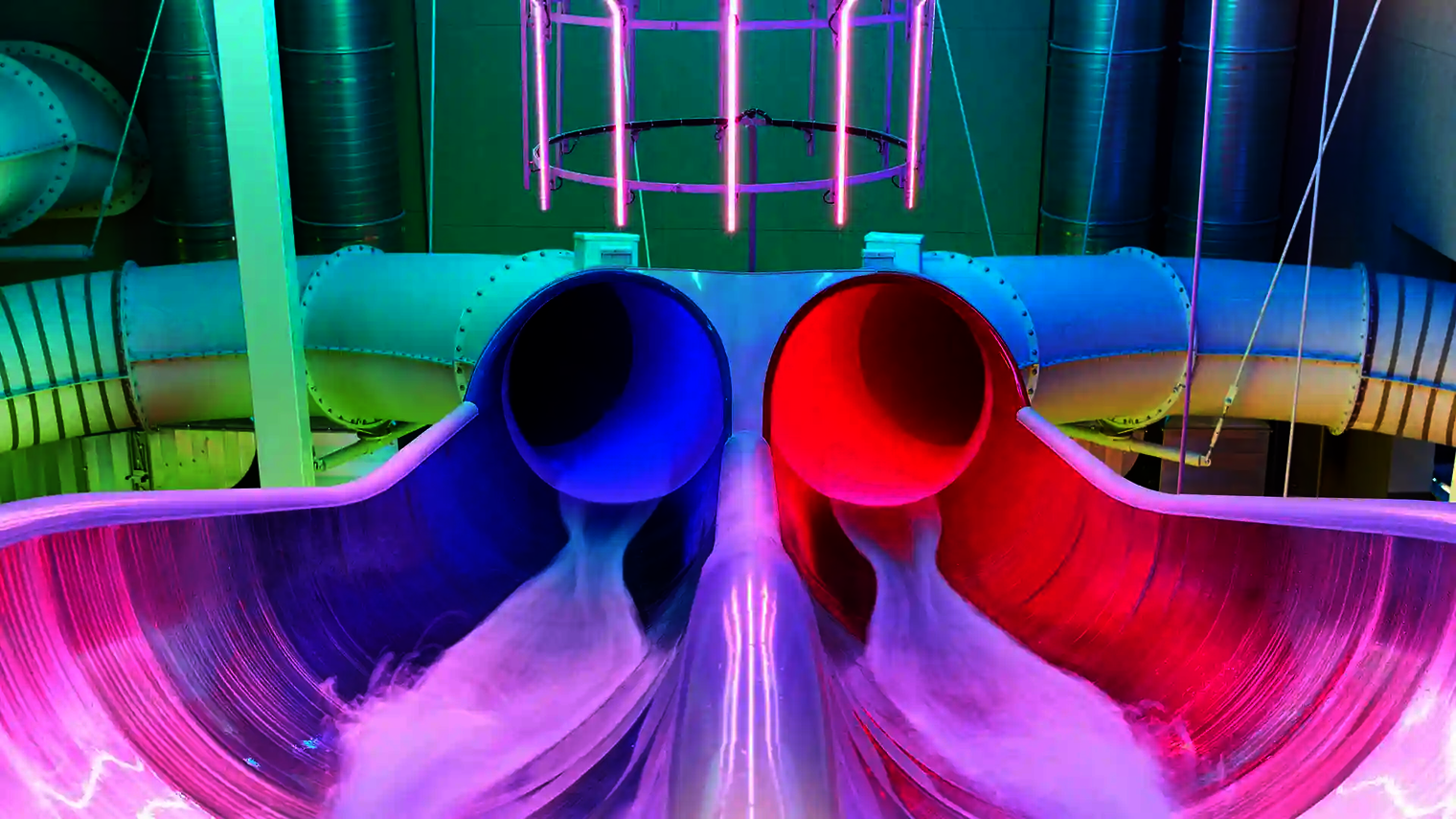 Die Raft Racer Reifenrutsche mit blau-roten Röhren und bunter LED-Beleuchtung in der Startzone.