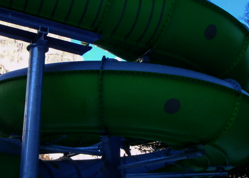 Grün lackierte Family Twister Wasserrutsche mit Metallstützen im Außenbereich.