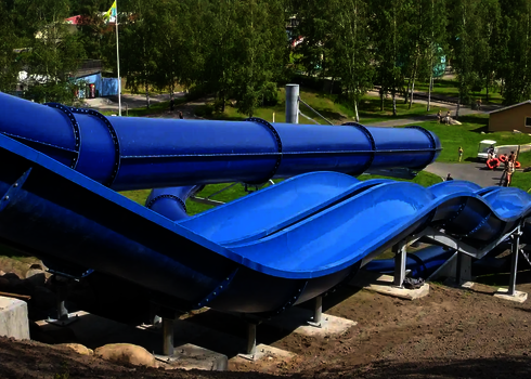 Seitlicher Blick auf blaue Harakiri Reifenrutsche mit geschwungenen Rutschbahnen.