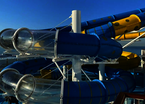 Mehrere transparente Acrylröhren verlaufen zwischen bunten Rutschenteilen auf einem Schiff.