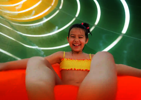 Kind sitzt lachen in Rutschreifen in einer grünen Röhrenrutsche mit Daylights.