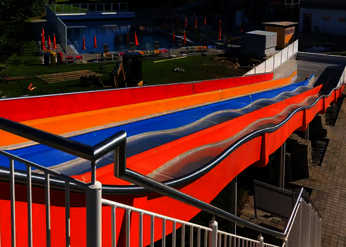 Bunte Multilane im Freibad mit roten, orangen und blauen Bahnen, Blick vom Startbereich.