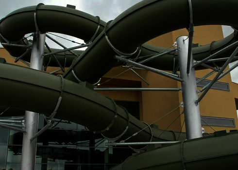 Eine olivgrüne Wasserrutsche außen an einem Gebäude.