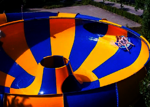 Zwei Personen rutschen in blauem Rutschreifen eine blau-gelbe Raft Bowl Rutsche.