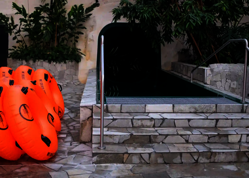 Mehrere orangefarbene Rutschreifen liegen am Auslauf einer grünen Tunnelrutsche.