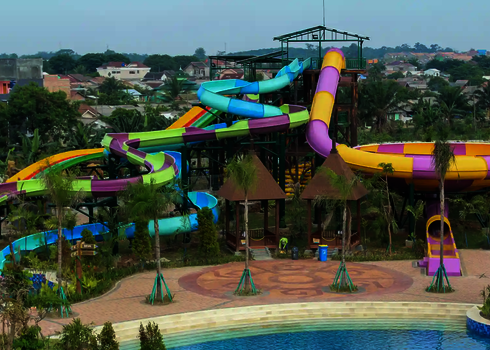 Weitsicht auf einen Wasserpark mit bunten Rutschen, umgeben von Bäumen.