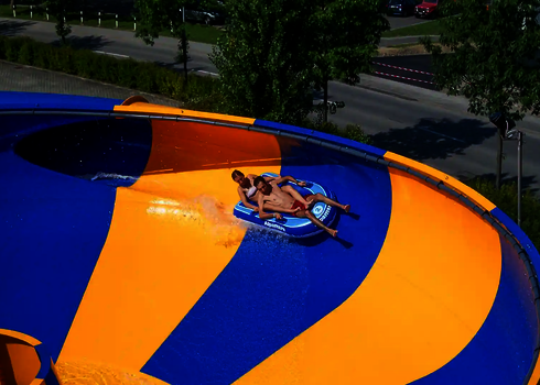 Nahaufnahme eines Raft Bowls mit zwei rutschenden Personen und einer Straße im Hintergrund.