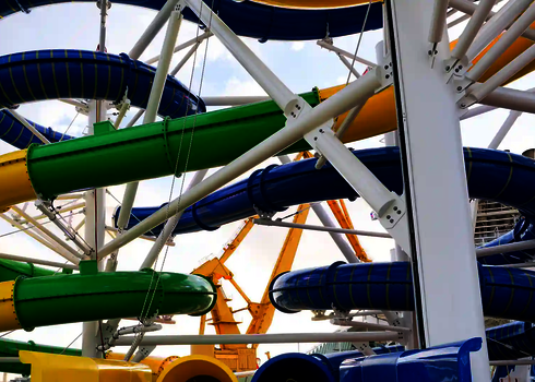 Bunte Wasserrutschen RR900 in grün, gelb und blau vor gelbem Kran im Hintergrund.