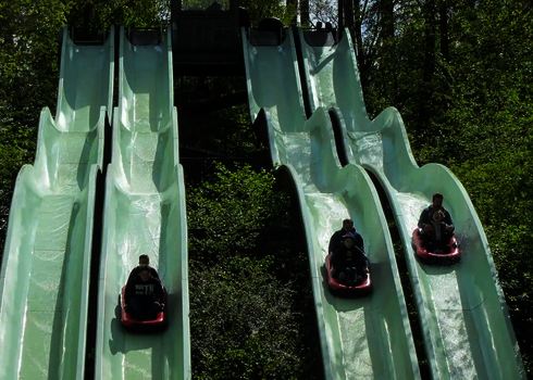 Mehrere Personen rutschen auf vier parallel laufenden Bahnen der Harakiri Freizeitparkrutsche. 
