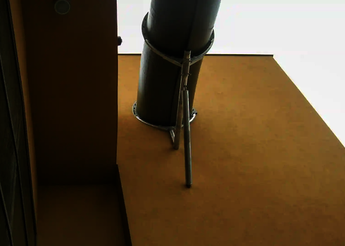 Blick von unten auf eine Wasserrutsche, die durch eine beige Gebäudefassade führt.