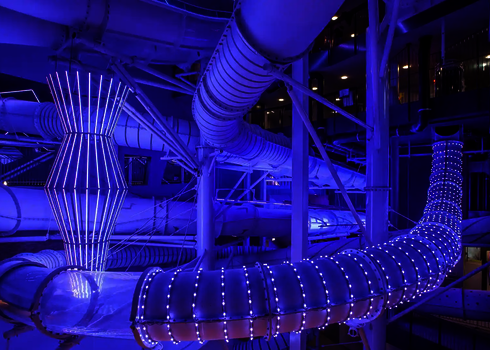 Verschlungene Röhrenrutschen mit LED-Streifen und auffälligen blauen Lichteffekten.