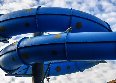 Blick von unten auf eine blaue GFK Wasserrutsche unter freiem Himmel.