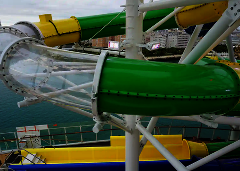 Eine Wasserrutsche auf einem Kreuzfahrtschiff mit grünem Rohr und transparentem Acryl-Teil über dem Meer.