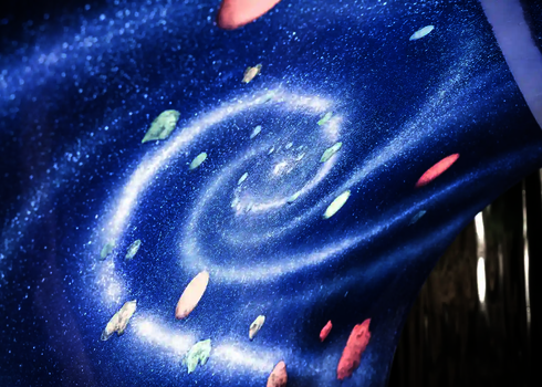 Glitzernde Spiralgalaxie mit bunten Elementen unter UV-Licht in einer Rutsche.