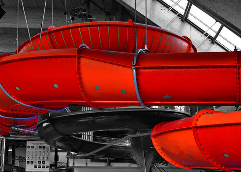 Orangene Family Twister Wasserrutsche in einer Halle mit Holzdachkonstruktion.