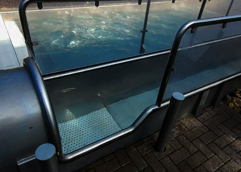 Close-up of the stainless steel slide exit with handrail and view into the tube.