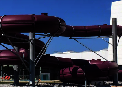 Dunkelrote gedämmte Wasserrutsche mit Metallstützen verläuft neben einem modernen Bad.