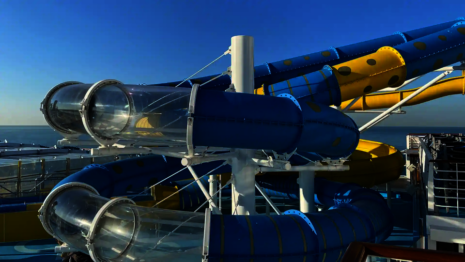 Eine blau gelbe RR1200 Wasserrutsche mit transparenten Acryl-Abschnitten auf einem Kreuzfahrtschiff.