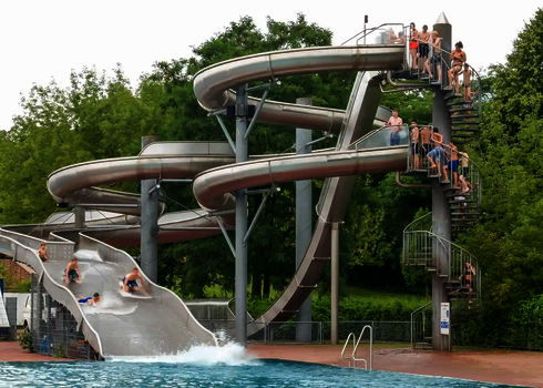 Ein Rutschenturm mit Badegästen, die für eine unterschiedliche Wasserrutschen anstehen.